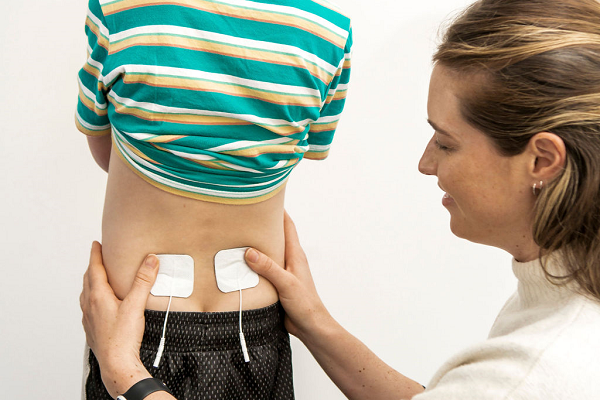 Physio putting electrodes on child's lower back