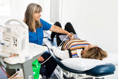 Woman lying down another woman doing a belly ultrasound